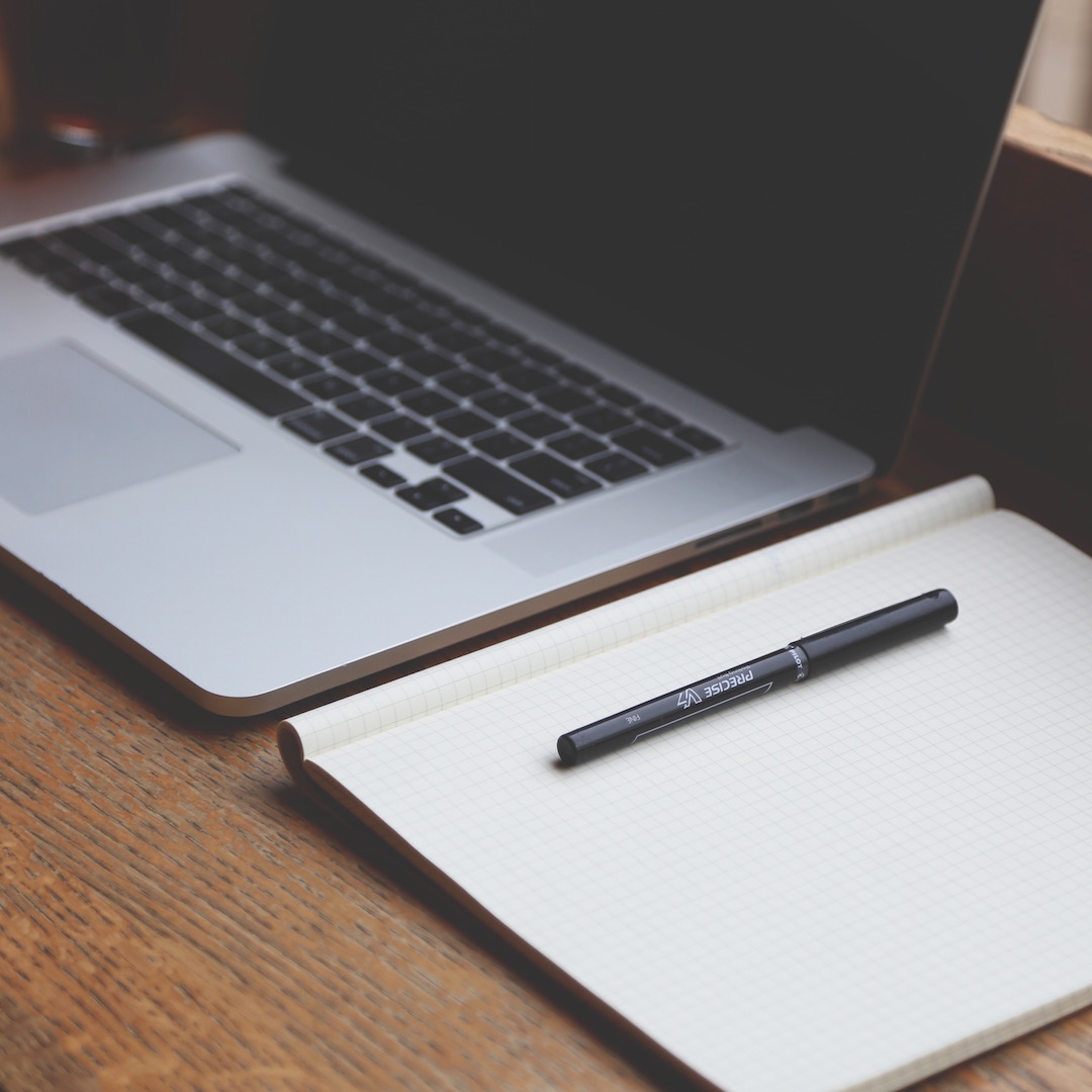 Notebook aberto ao lado de um laptop, sugerindo planejamento e organização